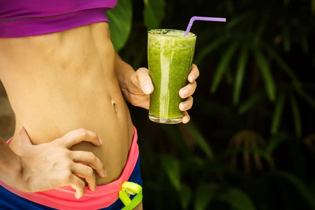 Athletic girl holding a green smoothie.
