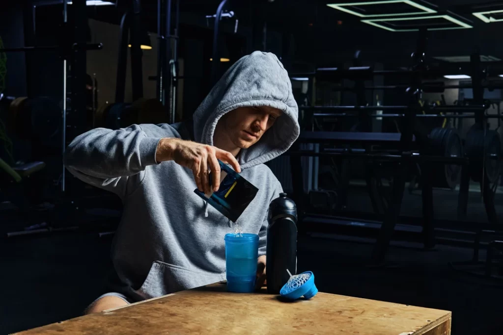 man pouring energy sports supplement in bottle.