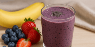 A vibrant berry smoothie blended with black beans, banana, strawberries, blueberries, and chia seeds, displayed in a glass with fresh fruits and black beans on the side.