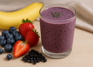 A vibrant berry smoothie blended with black beans, banana, strawberries, blueberries, and chia seeds, displayed in a glass with fresh fruits and black beans on the side.