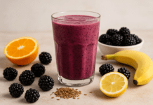 A rich purple smoothie made with blackberries, orange, lemon, banana, and flaxseed, surrounded by fresh fruit and seeds on a bright, rustic surface to highlight cardiovascular-supportive ingredients.