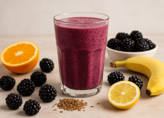 A rich purple smoothie made with blackberries, orange, lemon, banana, and flaxseed, surrounded by fresh fruit and seeds on a bright, rustic surface to highlight cardiovascular-supportive ingredients.