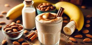 A creamy cinnamon almond smoothie in a clear glass, topped with a sprinkle of cinnamon. Surrounding the glass are almonds, a banana, a drizzle of honey, and a bottle of almond milk, highlighting brain-boosting ingredients.