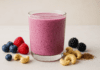 A vibrant heart-healthy smoothie made with soaked cashews, blueberries, raspberries, blackberries, and flaxseed, served in a clear glass and surrounded by fresh berries, cashews, and flax on a wellness-inspired minimalist background.