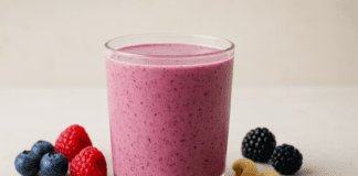 A vibrant heart-healthy smoothie made with soaked cashews, blueberries, raspberries, blackberries, and flaxseed, served in a clear glass and surrounded by fresh berries, cashews, and flax on a wellness-inspired minimalist background.